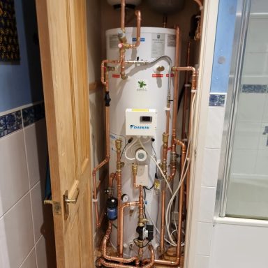 A water heater with copper piping installed in a bathroom.