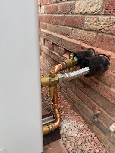 Pipework connected to a wall, featuring brass fittings and copper tubing.