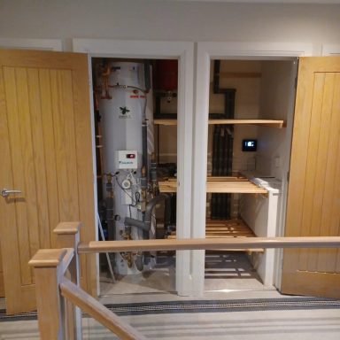 Two closet doors open, revealing a water heater on the left and an empty shelving unit on the right.