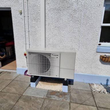 Air conditioning unit installed outside a building on a paved area.