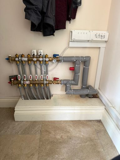 Heating system manifold with pipes and valves mounted on a wall.