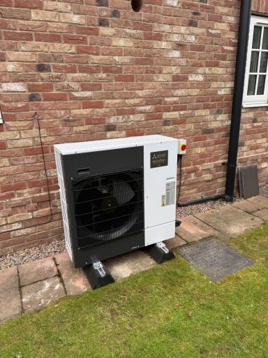 A white outdoor air conditioning unit against a brick wall.